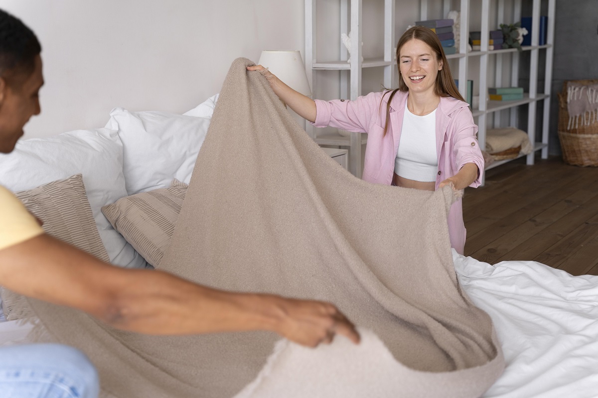 Casal arrumando roupa de cama de seu quarto Casal arrumando roupa de cama de seu quarto